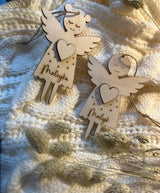 Zwei personalisierte Schutzengel aus Holz mit den gravierten Namen Maleyka und Malyk auf einer weißen Strickdecke