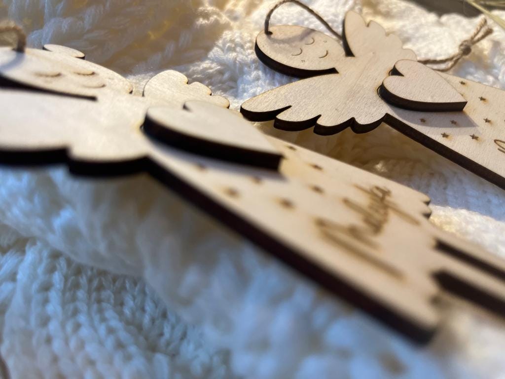 Nahaufnahme der Schutzengel aus Holz: gravierte Sterne und Name auf dem Engelskleid